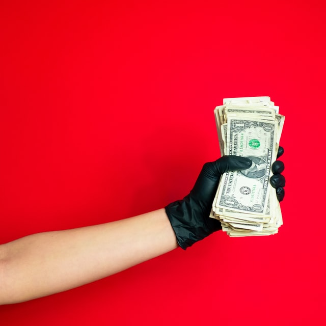 An individual holding one dollar bills
