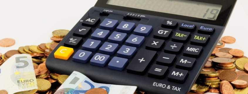 a calculator, notes, and coins on a table