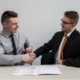two men shaking hands after signing a loan contract