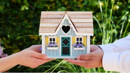 two people holding a miniature house model